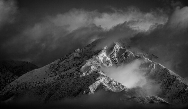 Black and White image of Mountains in Angeles National Forest covered in snow during a storm. The shot is looking west from the 15 freeway at the Limonite Ave park and ride in Mira Loma Ca