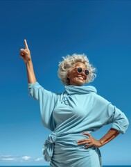 Smiling woman pointing fingers up over blue sky on sea shore