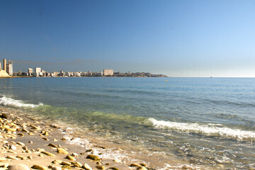 Mediterranean coast in winter, stones, sunny day. High rise buildings in the distance. 