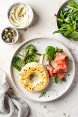 Homemade bagel sandwich with smoked salmon, cream cheese, capers and spinach for healthy breakfast top view