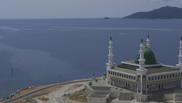 Aerial view of the magnificent beautiful Baitul Makmur Great Mosque, Tarempa. Mosque building by the sea with white paint and green dome. Eid al-Fitr Eid al-Adha Concept.