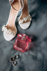 A modern composition of elegant wedding accessories for an attractive bride. Wedding rings, wedding bouquets, bottle of perfume, elegant fashionable shoes, jewelry. Preparation of the bride