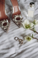 A modern composition of elegant wedding accessories for an attractive bride. Wedding rings, wedding bouquets, bottle of perfume, jewelry. Preparation of the bride