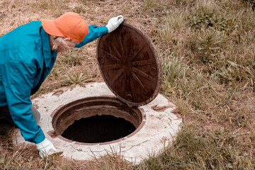 A male plumber inspects a water well. Repair of plumbing and water meters.