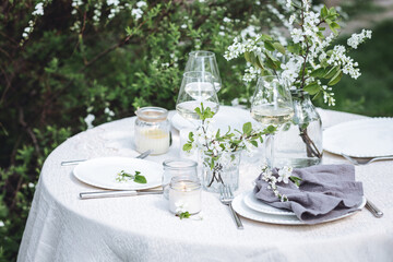Rustic zero waste wedding decor with natural elements. Fresh spring blooming flowers, candles, linen napkins, wine glasses. Eco friendly decoration for the special holiday dinner. Romantic cozy place