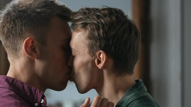 Authentic close up of affectionate attractive homosexual couple with eyes closed passionately kissing, expressing love, sexual attraction and strong relationship indoors. High quality 4k footage