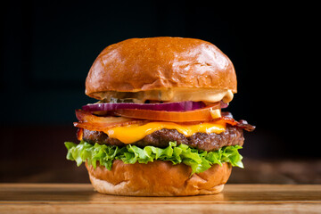 Bacon cheeseburger on a wooden board in a restaurant - obrazy, fototapety, plakaty