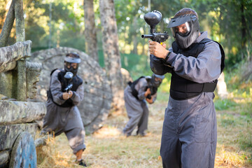 Fototapeta premium Man eliminating opponents on paintball field. Man in protective outwear and helmet targeting with paintball marker.