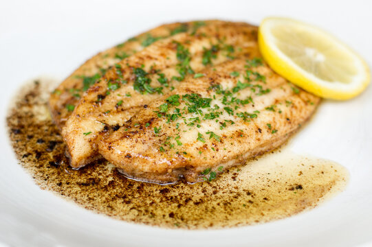 Fried common sole fillets on a white plate with lemon