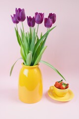 Tulips in yellow vase and strawberry in yellow cup