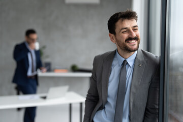 Fototapeta premium Happy young businessman looking through window
