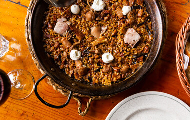 On rustic wooden table there is hearty and healthy country lunch - crumbly paella with mushrooms...