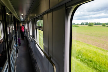 Passenger train interior shot, train going through green planes visible behind windows, inside, Eastern Europe travel, traveling by train, comfy cozy scene, background, perspective, anonymous people