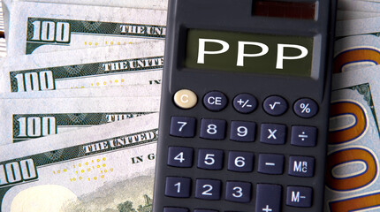 PPP - acronym written on a calculator on the background of banknotes