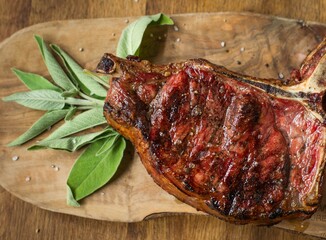 Cooked T-Bone steak with sage on wooden plank