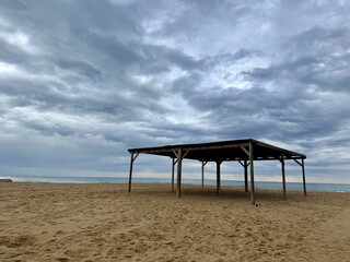 Fototapeta na wymiar beautiful abandoned beach with wooden canopy tent and vivid sky. Empty sea shore not in season. Sea beach scenery