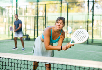 Padel game - woman with partners plays on the tennis court