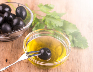 Olive oil with fresh herbs and olives on wooden background. on sunlight