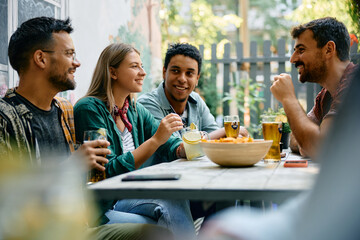 Happy woman enjoys in conversation with her friends while having drink in cafe.