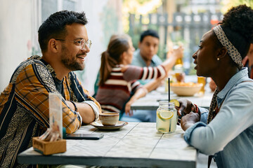 Happy man talking to his black girlfriend in cafe.