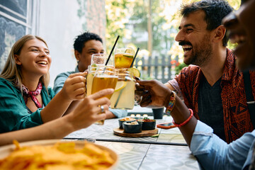 Group of happy friends having fun and toasting with drinks in cafe.