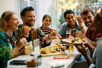 Cheerful friends enjoying in Mexican food in restaurant. - obrazy, fototapety, plakaty