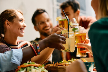 Close up of friends toasting while having lunch in restaurant.