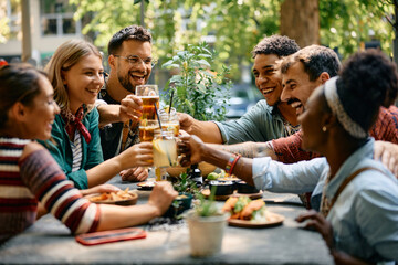 Cheerful group of friends toasting while gathering for drink in cafe.