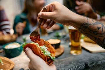 Rolgordijnen Close up of man having tacos while eating in Mexican restaurant. © Drazen