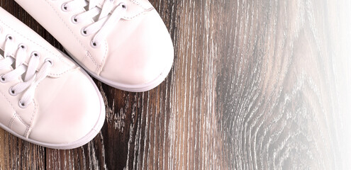 White sneakers on dark wooden surface. Shoes for women in sport fashion style