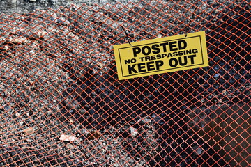 Keep out placard zip tied to orange construction mesh fencing.