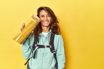 Middle aged woman with backpack and spaghetti can on yellow backdrop