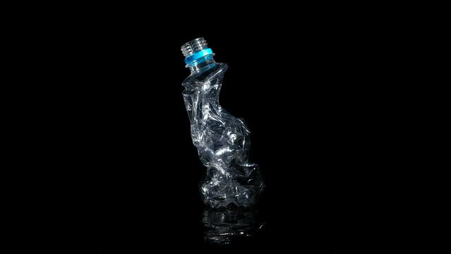 Crushed plastic bottle on black background. A crushed drinking plastic bottle rotating on the blak background.