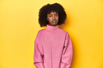 Obraz na płótnie Canvas Teen girl in pink sweatshirt, yellow studio backdrop sad, serious face, feeling miserable and displeased.