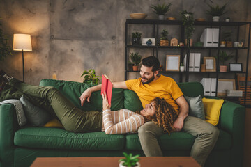 man and woman caucasian adult couple read book at home on sofa bed