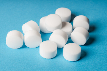 White salt tablets for softening water in a softener on a blue background
