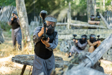 Fototapeta premium Excited paintball player in protective uniform aiming and shooting with guns
