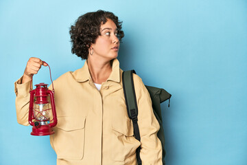 Young traveler woman with backpack and lantern, adventure concept, studio shot.