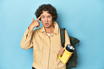 Traveler woman with vintage camera and flashlight showing a disappointment gesture with forefinger.