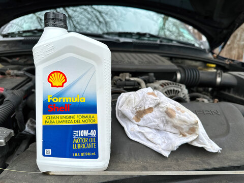 NORWALK, CT, USA - FEBRUARY 11, 2024: Bottle with Shell motor oil SAE 10W 40    on car with open hood