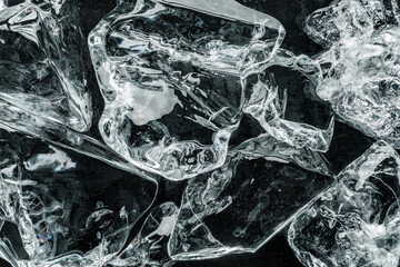 Pieces of crushed ice on black background. Abstract ice structure background, top view