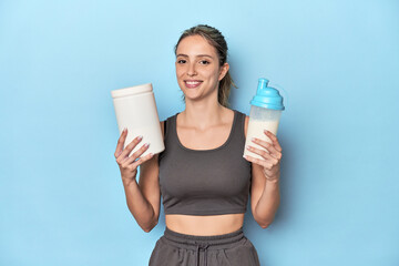 Athlete with protein shake and container in blue studio