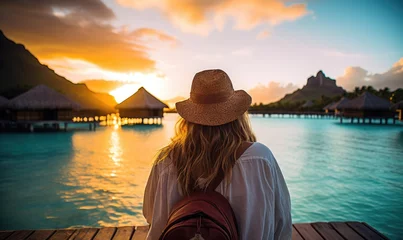 Fototapete Bora Bora, Französisch-Polynesien Tropical Serenity: Back View of a Happy Tourist Woman Relaxing on the Deck of an Overwater Bungalow in Bora Bora, Embracing the Tranquil Beauty of Sunset Over the Turquoise Lagoon.  