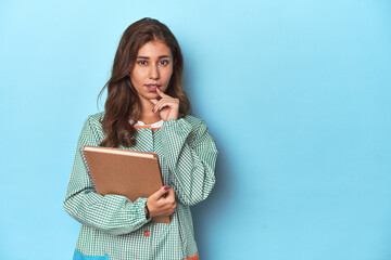 Young teacher holding notebooks, imparting knowledge relaxed thinking about something looking at a copy space.