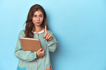 Obraz premium Young teacher holding notebooks, imparting knowledge showing number one with finger.