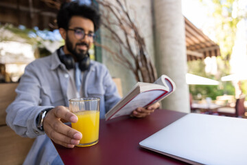 Young man spending time in a cafe and reading a book