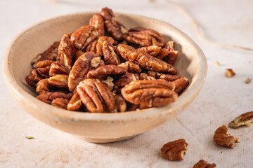 Tasty pecan nuts in a bowl on beige background