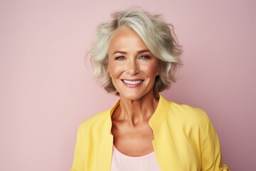 Cheerful senior woman. Beautiful mature woman looking at camera and smiling while standing against pink background