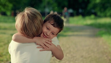 Mom Kid have fun playing outdoor. Happy boy child runs to mom in summer park, hugging mom. Family holiday. Young mother with son hug in nature. Family meeting mom with kid in park. Family, child walk