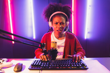 Host channel of gaming streamer, African girl taking, typing with Esport skilled team player and viewers online game in neon color lighting room. Concept of cybersport indoor activities. Tastemaker.